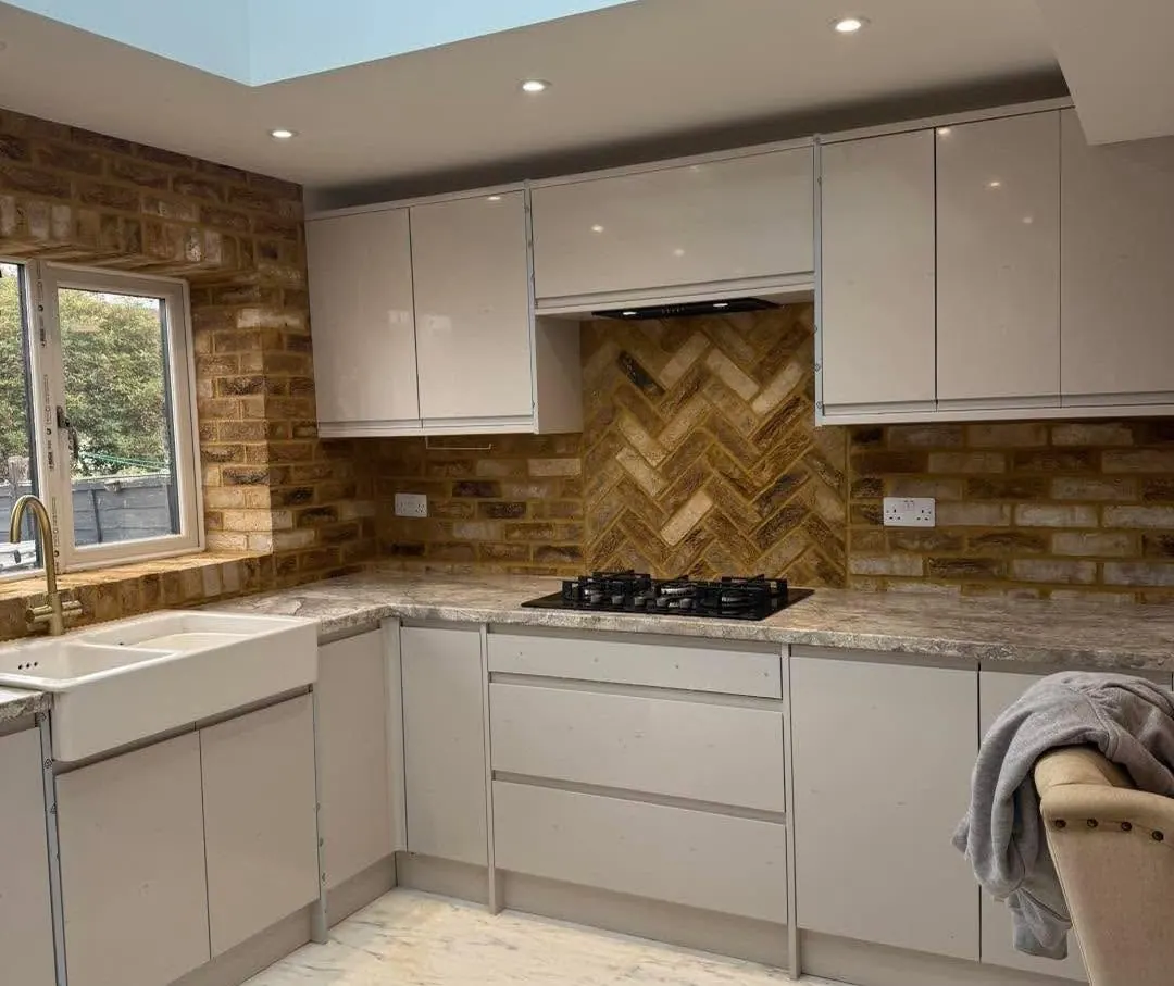 Warm brown brick slip kitchen walls with a herringbone panel behind the hob