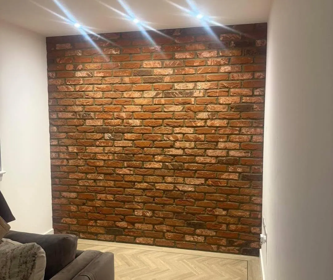 Red brick slip feature wall lit by ceiling downlights, fitted from our own brick slip supply