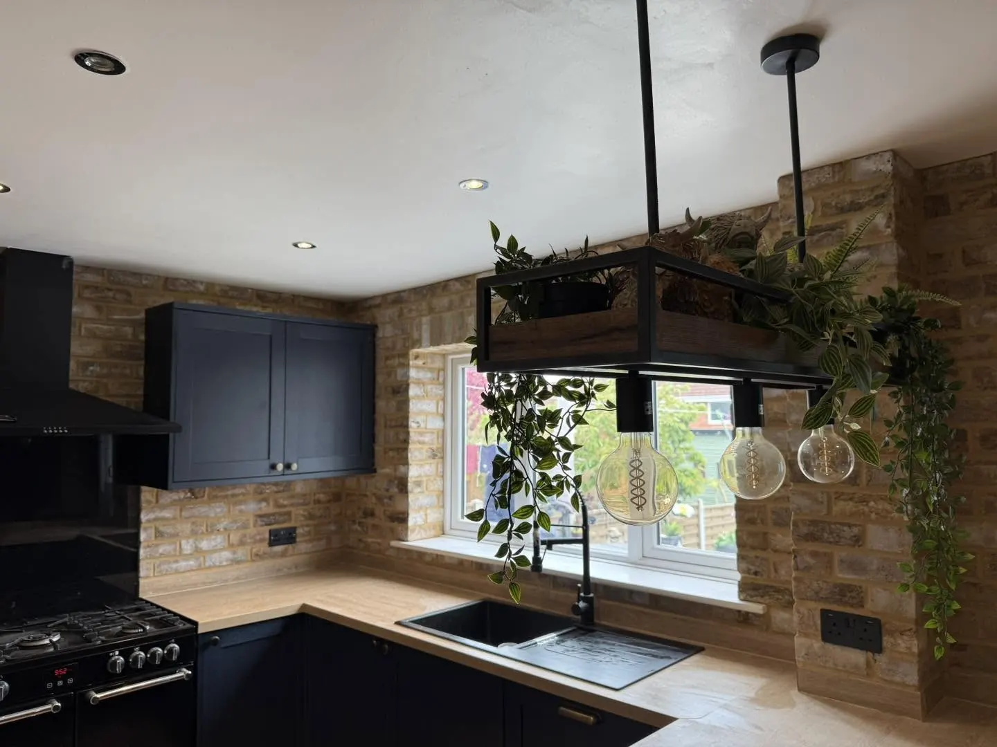 Navy kitchen with brick slip walls and pendant lighting