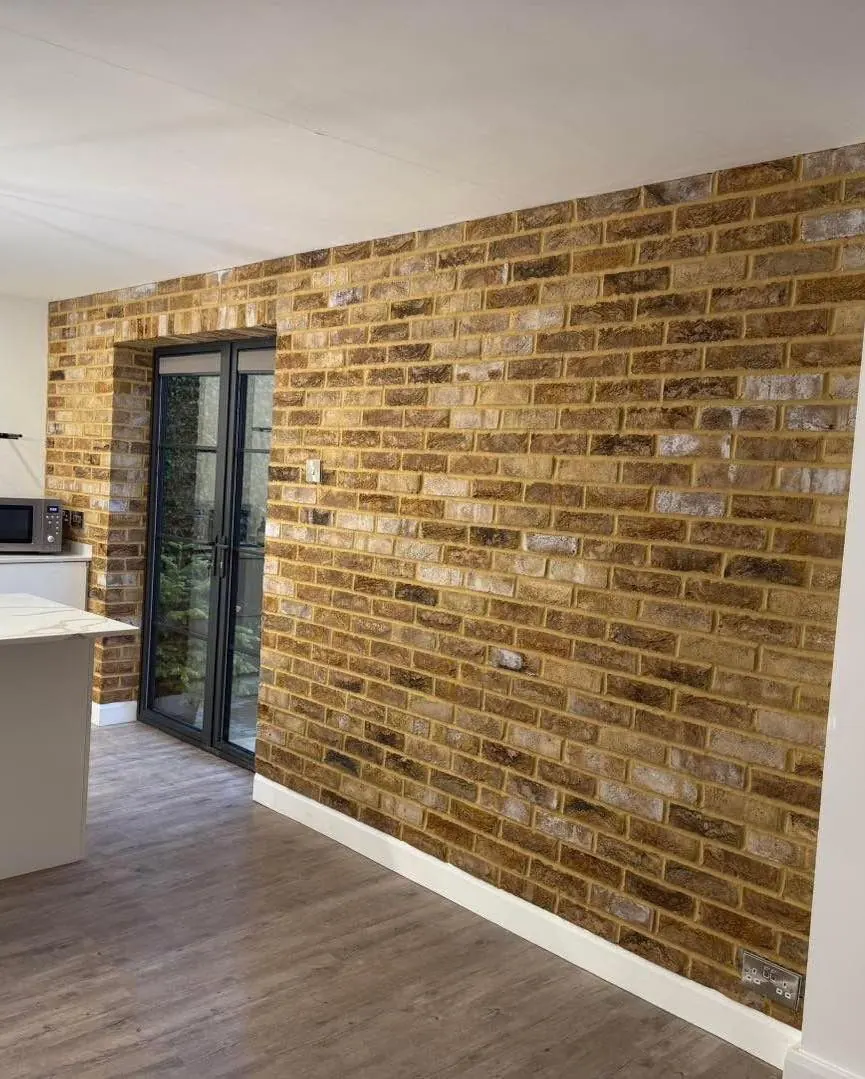 Long warm brown brick slip feature wall beside a kitchen doorway