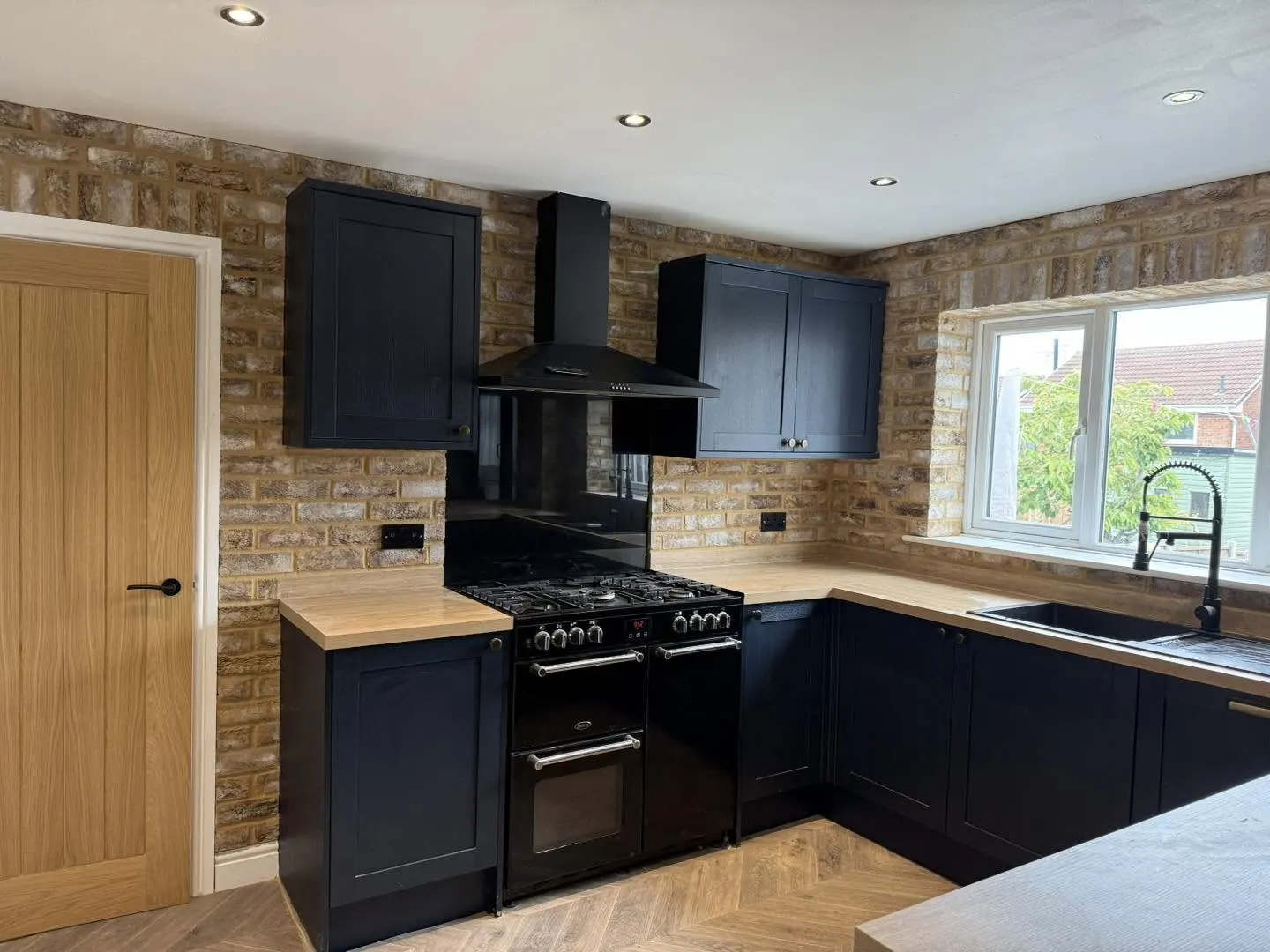 Pale warm brick slip walls in a navy fitted kitchen