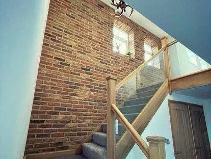 Red brick slip feature wall running alongside a staircase