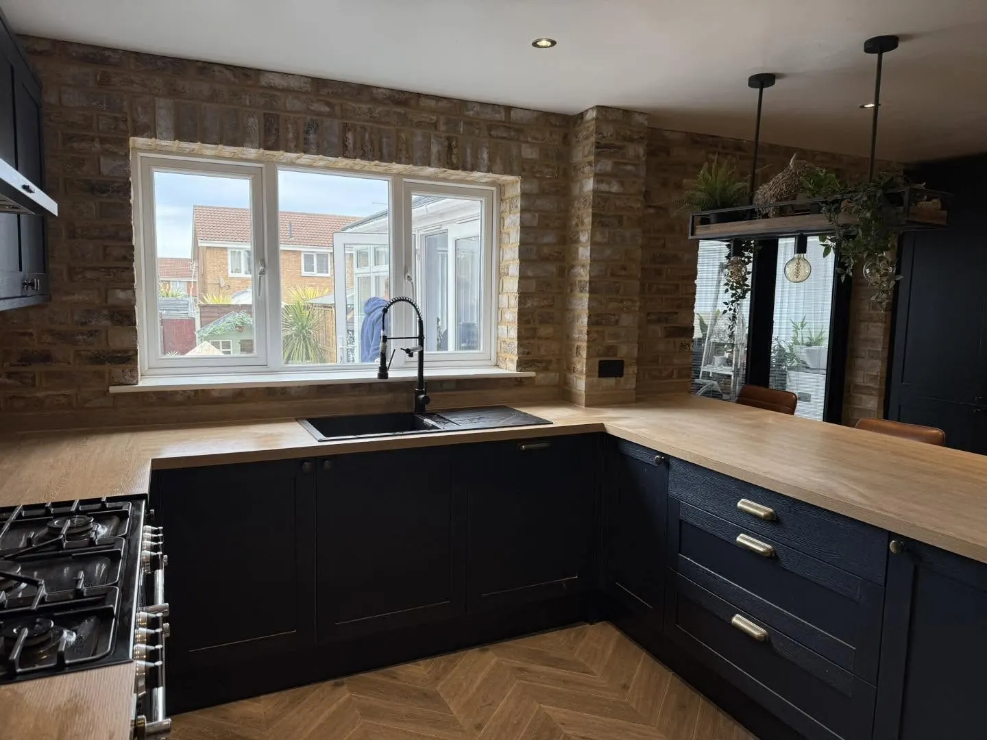 Brick slip walls around the window and sink of a navy kitchen