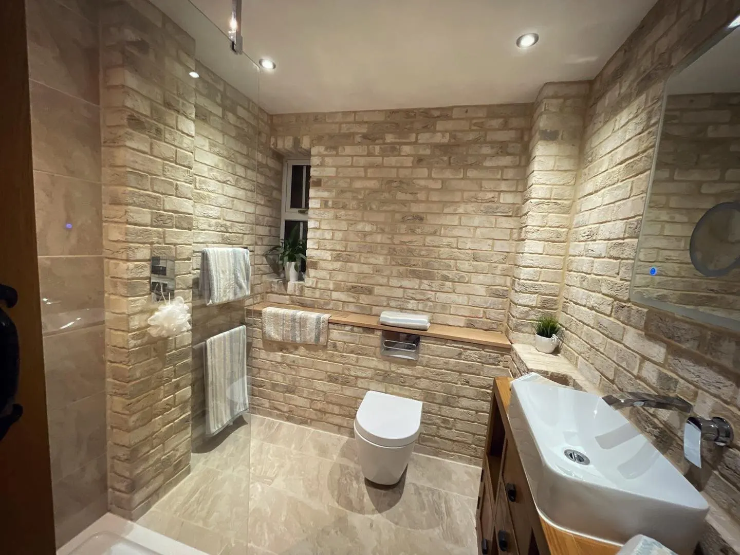 Pale brick slip bathroom walls with a glass shower enclosure and vanity