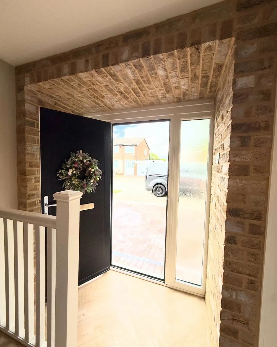 Brick slip hallway arch around a black front door after installation
