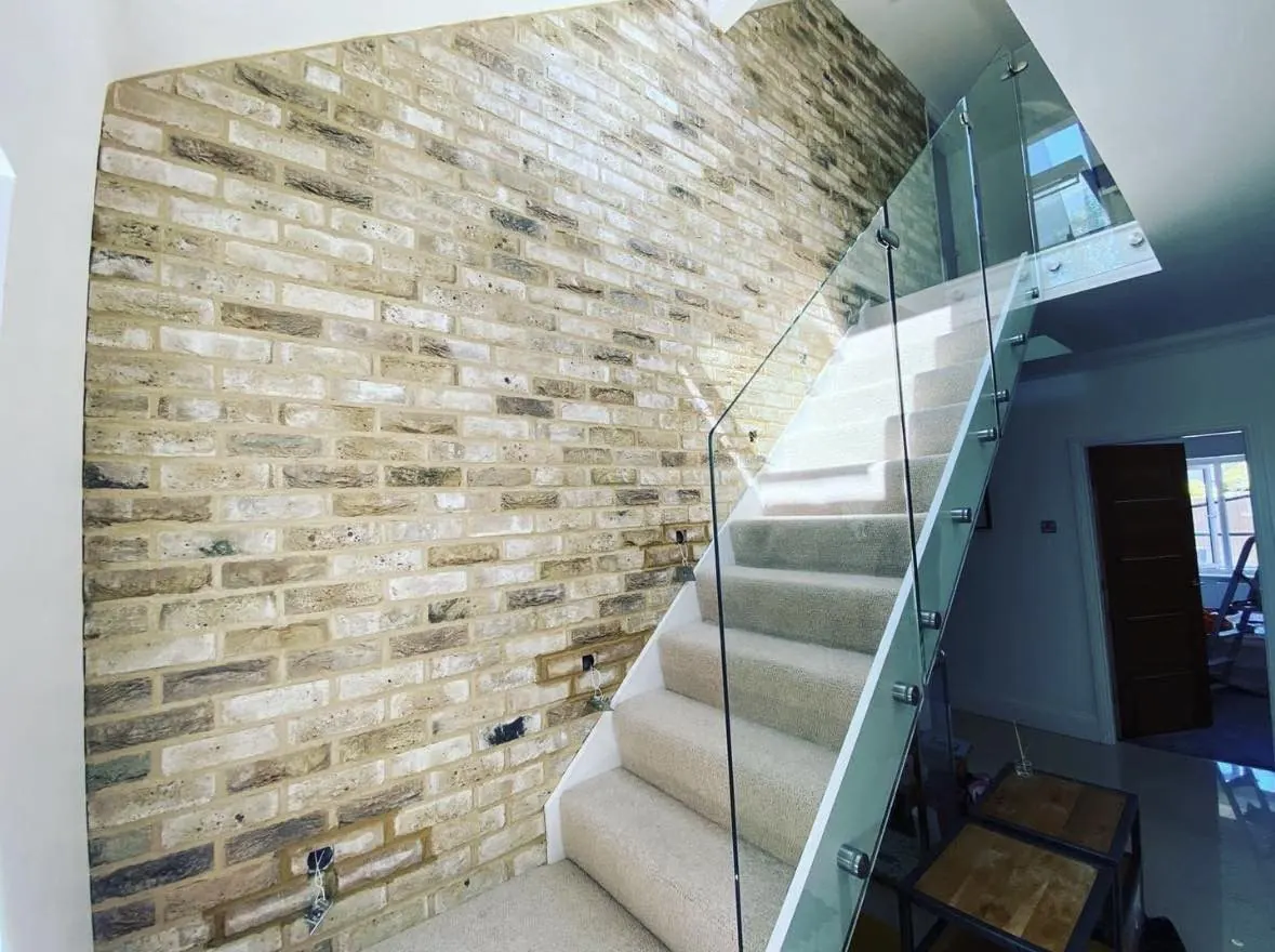 Pale yellow brick slip staircase wall with a glass balustrade