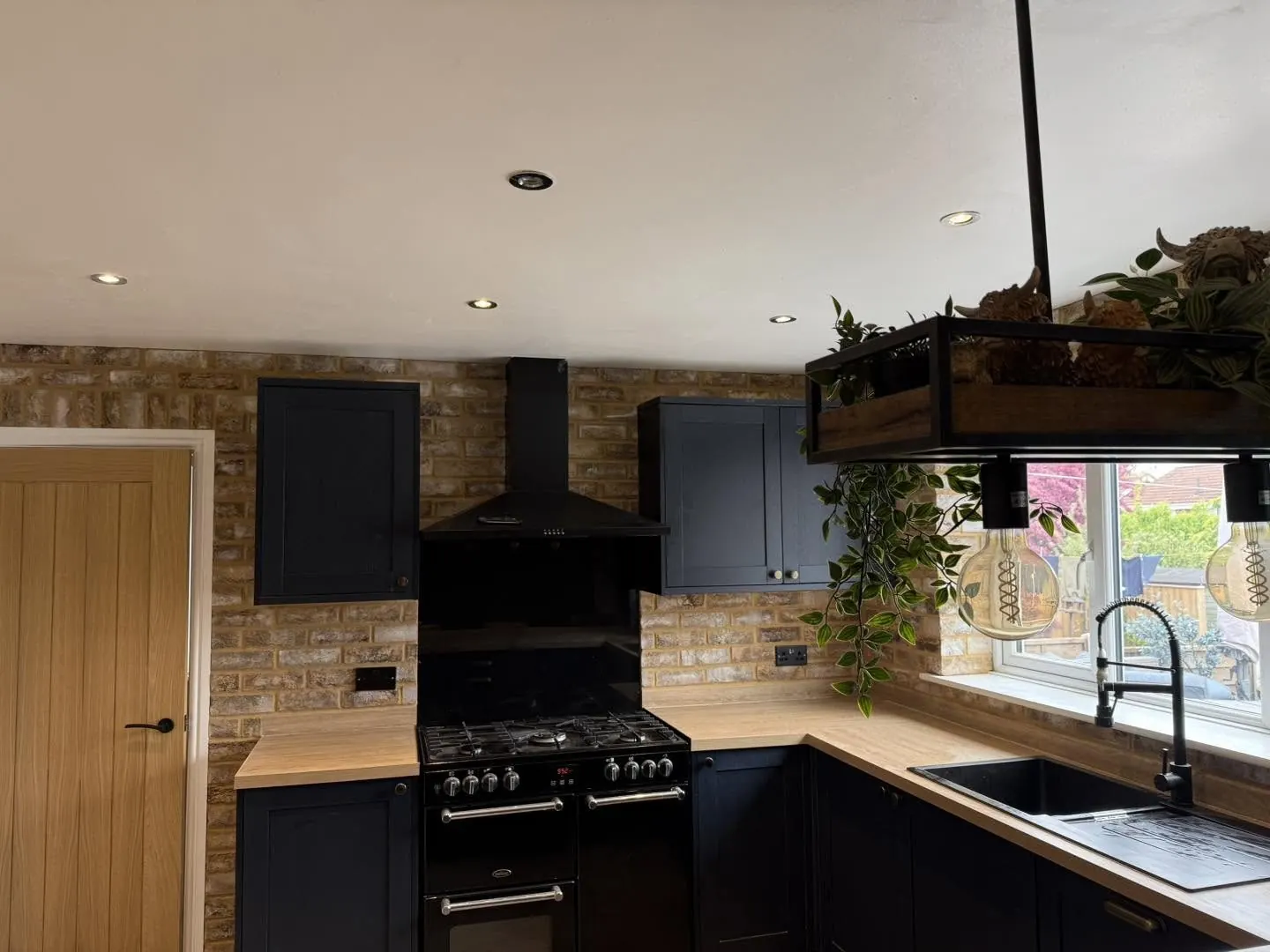Navy kitchen with brick slip walls behind the cooker