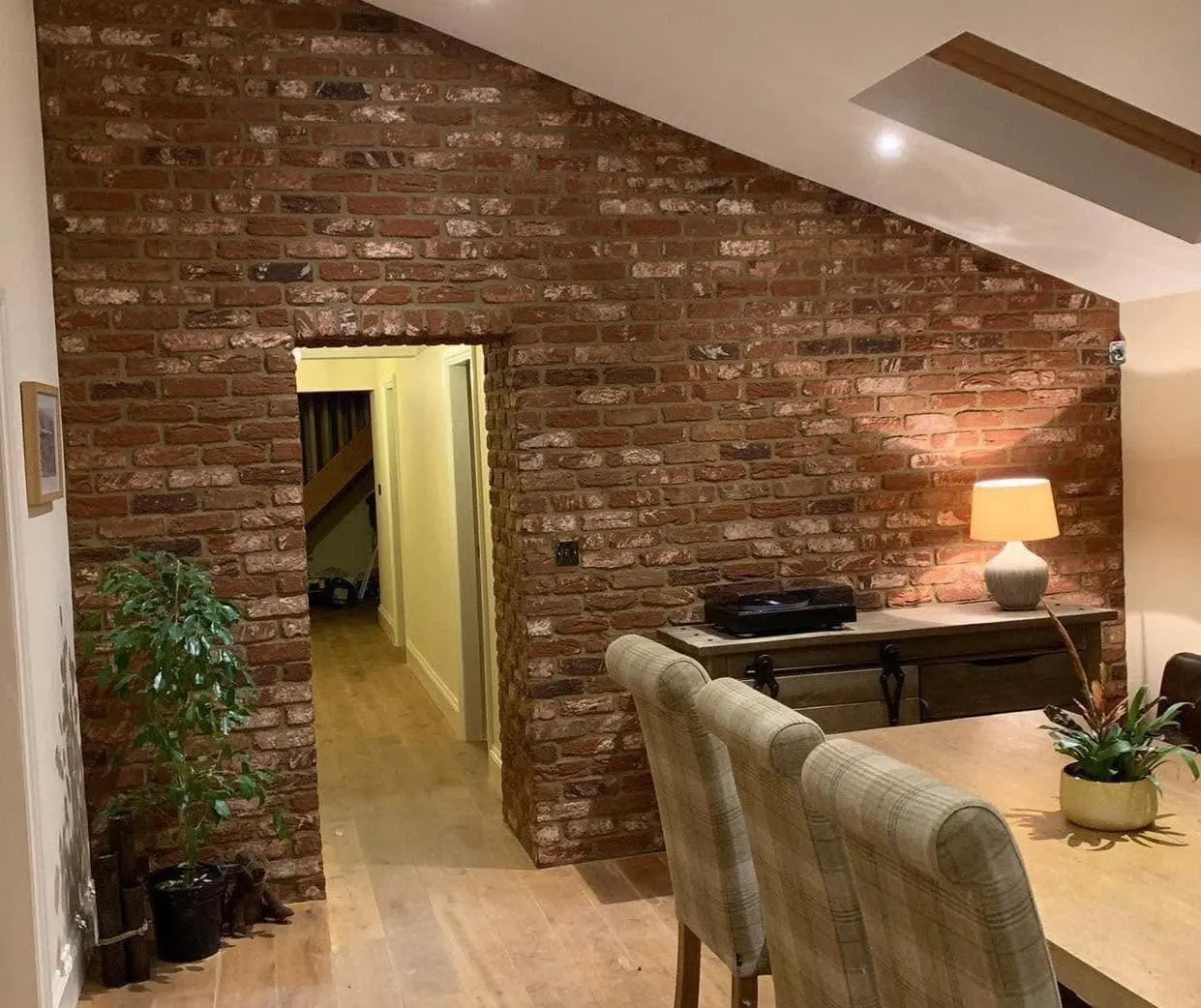 Red brick slip feature wall around a doorway under a sloping ceiling